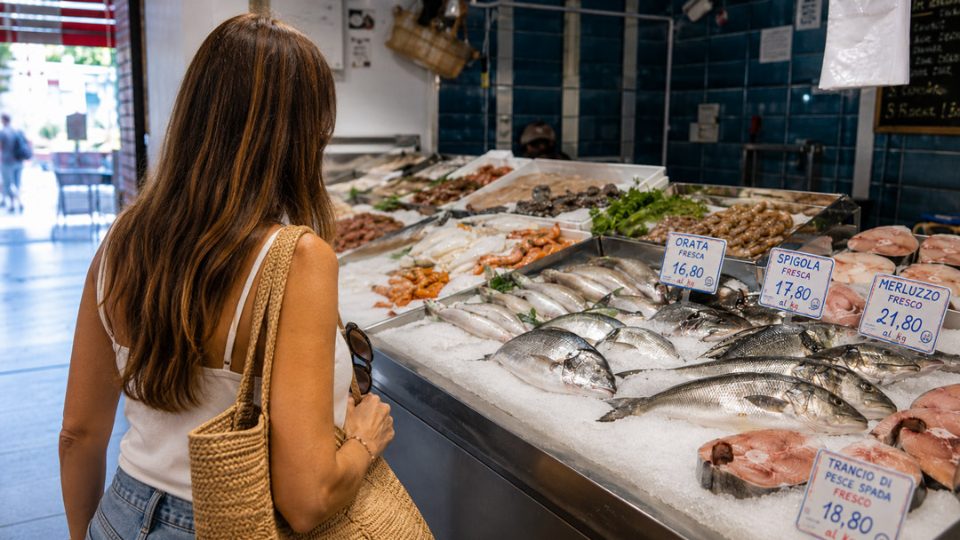 Dona analizza pesce fresco su banco