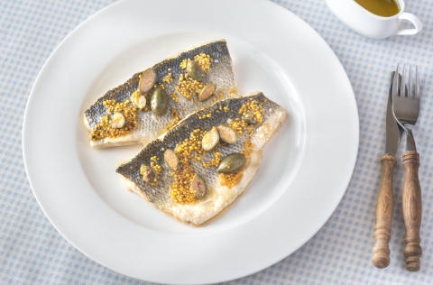 Lomos de dorada sobre plato y mesa puesta