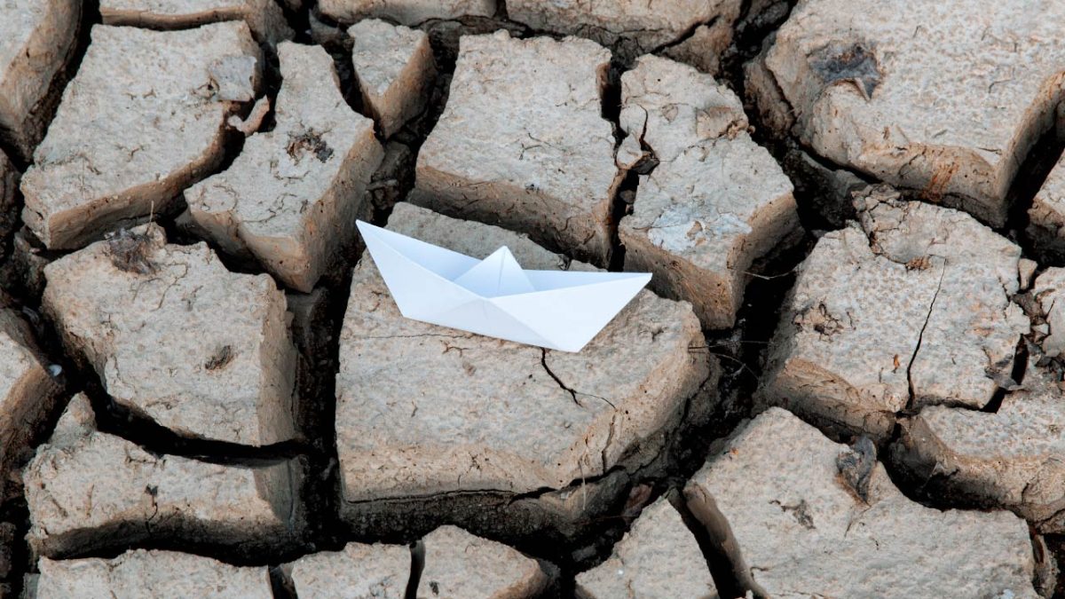 Barco de papel en tierra seca