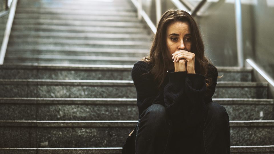 Mujer sentada en escalera con cara de preocupación